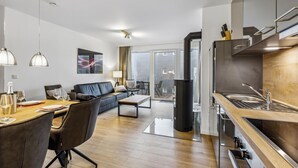 Eine moderne Wohnung mit Essbereich, Wohnzimmer mit Sofa, Küche mit Herd und einer Schiebetür zum Balkon.