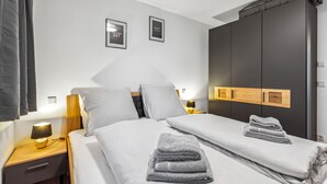 Ein Hotelzimmer mit einem Bett, zwei Nachttischen mit Lampen, einem Kleiderschrank und zwei gerahmten Motivationspostern an der Wand.