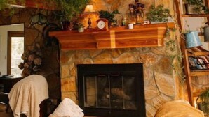 Una sala de estar acogedora con chimenea de piedra, estantes de madera y una escalera.