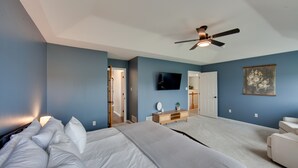 A bedroom with a bed, a ceiling fan, a TV, a door, and a painting on the wall. - Game Room & Covered Patio: Hummelstown Hideaway (Hummelstown)