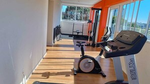 Un gimnasio con cintas de correr, una bicicleta estática y una máquina de remo.