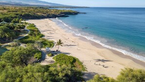Une plage à l’eau d’un bleu limpide, bordée d’un rivage sablonneux et d’une végétation luxuriante.