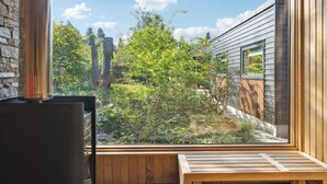 A modern room with a large window overlooking a lush garden and a wooden deck. - Awesome home in Væggerløse with kitchen (Væggerløse)