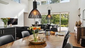 A modern kitchen with a dining area, featuring a large wooden table, black chairs, and pendant lights. - Awesome home in Væggerløse with kitchen (Væggerløse)