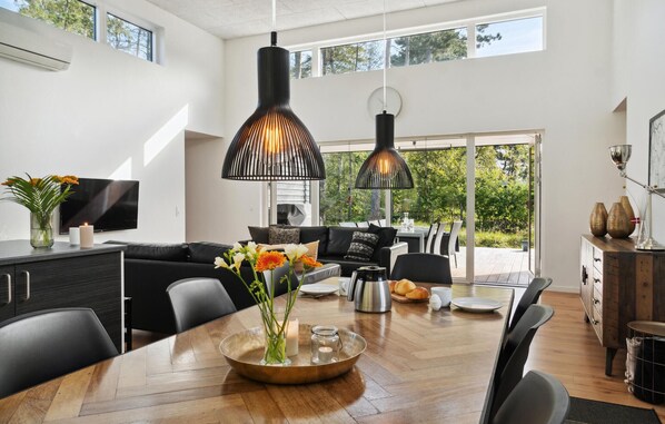 Een moderne keuken met een eetgedeelte, met een grote houten tafel, zwarte stoelen en hanglampen.