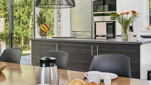 A modern kitchen with a dining table set for breakfast, including croissants and coffee. - Awesome home in Væggerløse with kitchen (Væggerløse)