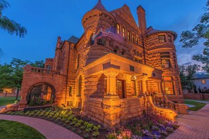 A historic stone building with a turret, a flag, and a well-maintained garden. - Orman Mansion - Pueblo's Most Luxurious Stay (Pueblo)