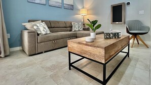 Una sala de estar con sofá, mesa de centro, lámpara y televisor.