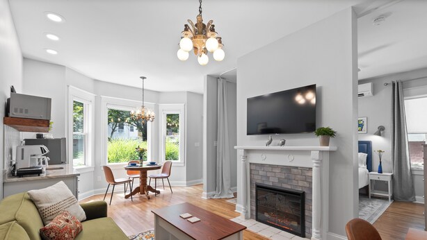 A modern living room with a fireplace, a television, and a dining area with natural light.