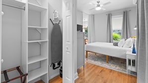 A bedroom with a bed, a wardrobe, a ceiling fan, and a window with curtains.