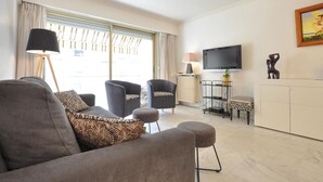 Un salon avec un canapé, des fauteuils, un téléviseur et un radiateur.