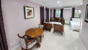 A compact living space with a dining area, a sofa, and a bed. - Periwinkle - Upscale Studio w Pool Near Beach
 (Nassau)