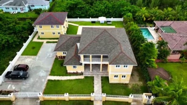 A large, multi-story house with a central courtyard, surrounded by lush greenery and a swimming pool. - Green Turtle - Upscale Studio w Pool Near Beach
 (Nassau)
