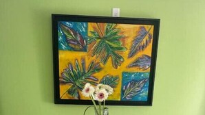 A round wooden table with two chairs, a vase with flowers, and a colorful painting on the wall. - Green Turtle - Upscale Studio w Pool Near Beach
 (Nassau)