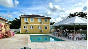 A two-story building with a swimming pool and a covered outdoor area with tables and chairs. - Green Turtle - Upscale Studio w Pool Near Beach
 (Nassau)
