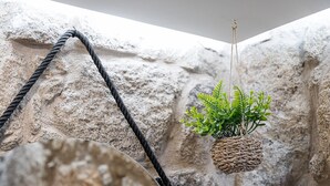 A hanging woven basket with a green plant against a textured stone wall. - GuestReady - Boutique style loft in Constituição (Porto)
