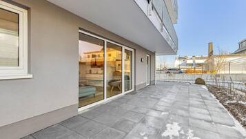 Ein modernes Gebäude mit überdachter Terrasse, großen Schiebeglasfenstern und Blick auf die Umgebung.
