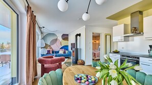 A modern living room with a sofa, a dining table with a plate of colorful macarons, and a kitchen area with a stove and cabinets. - Gorgeous apartment in Winterberg (Winterberg)