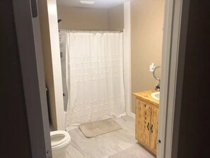 Une salle de bain avec douche, toilettes et meuble en bois.