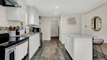 Una cocina moderna con armarios blancos, una estufa negra y piso de madera.
