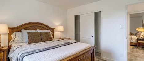 Ein Schlafzimmer mit einem hölzernen Bett, zwei Nachttischlampen, einem gemusterten Teppich und einer Tür zu einem anderen Raum.