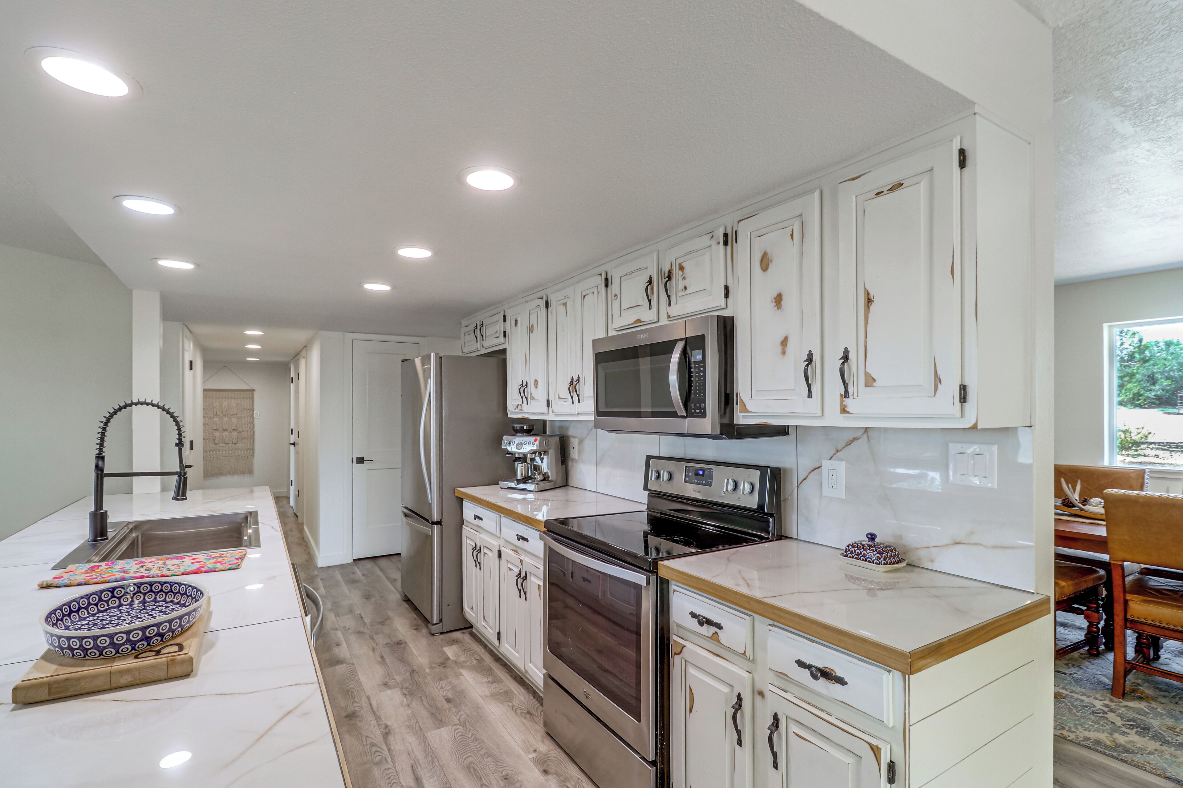 A modern kitchen with white cabinetry, stainless steel appliances, and a wooden countertop.