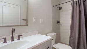 Un baño con lavamanos blanco, inodoro y cortina de ducha.