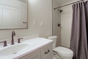 Un baño con lavamanos blanco, inodoro y cortina de ducha.