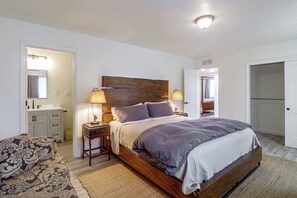 Un dormitorio con una cama de madera, lámparas de noche, un sofá estampado y una mesita.