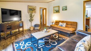 A living room with a flat-screen TV, a wooden coffee table, a sofa, and a patterned rug.