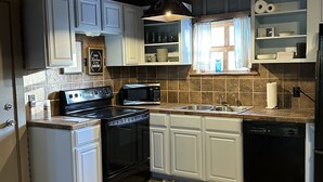 A kitchen with white cabinets, a black stove, a microwave, and a dishwasher. - Texan barn apartment awaits your arrival ! (Waxahachie)