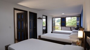 Une chambre d’hôtel avec deux lits, un balcon offrant une vue agréable et un bureau avec une lampe.