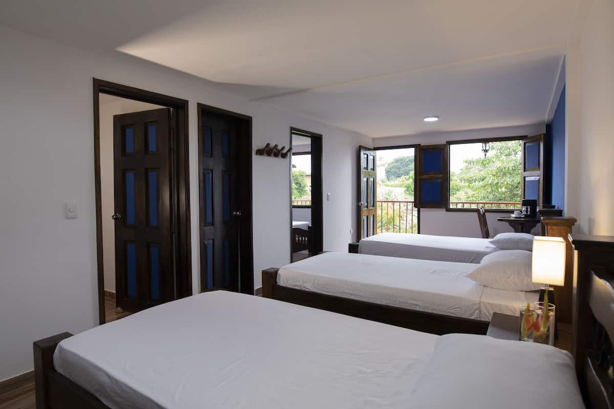 Ein Hotelzimmer mit zwei Betten, einem Balkon mit Blick und einem Schreibtisch mit Lampe.