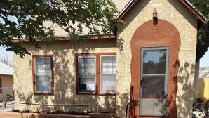 Un pequeño edificio con fachada marrón, una puerta y dos ventanas.