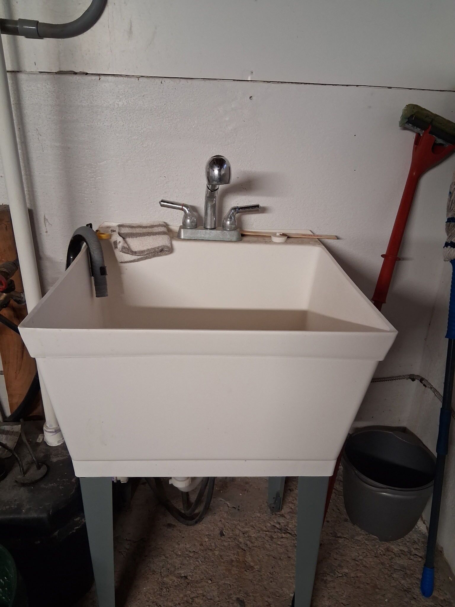 A white rectangular sink with a single faucet, mounted on a metal stand.