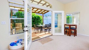 A room with a sliding glass door leading to an outdoor patio with a table and chairs. - 25% Off Sep 3-6! Perfect 4 Families -Pool, Jacuzzi (Palm Springs)