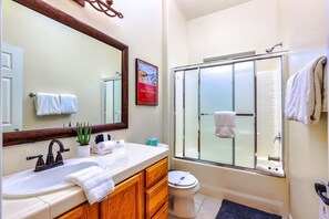 Une salle de bain avec un grand miroir, un lavabo avec une serviette, des toilettes et une douche.