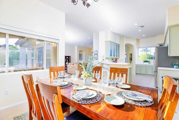 A dining area with a wooden table set for six, surrounded by chairs. - (Palm Springs)