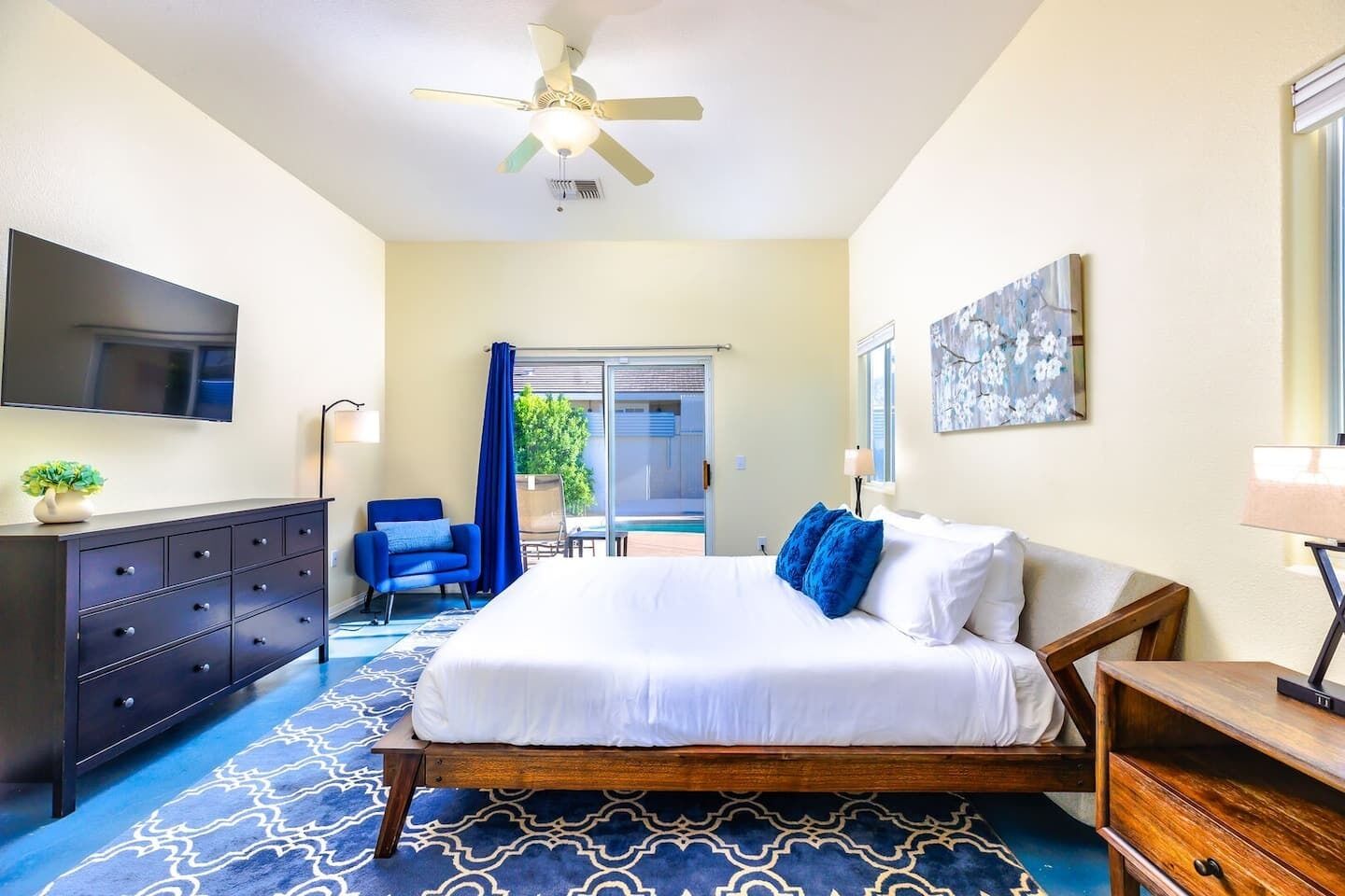 A hotel room with a bed, a TV, a desk, a chair, and a balcony with a view.