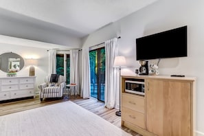 Relax in a spacious room with a large bed, flat-screen TV, and sliding glass door leading to an outdoor area with a view.
