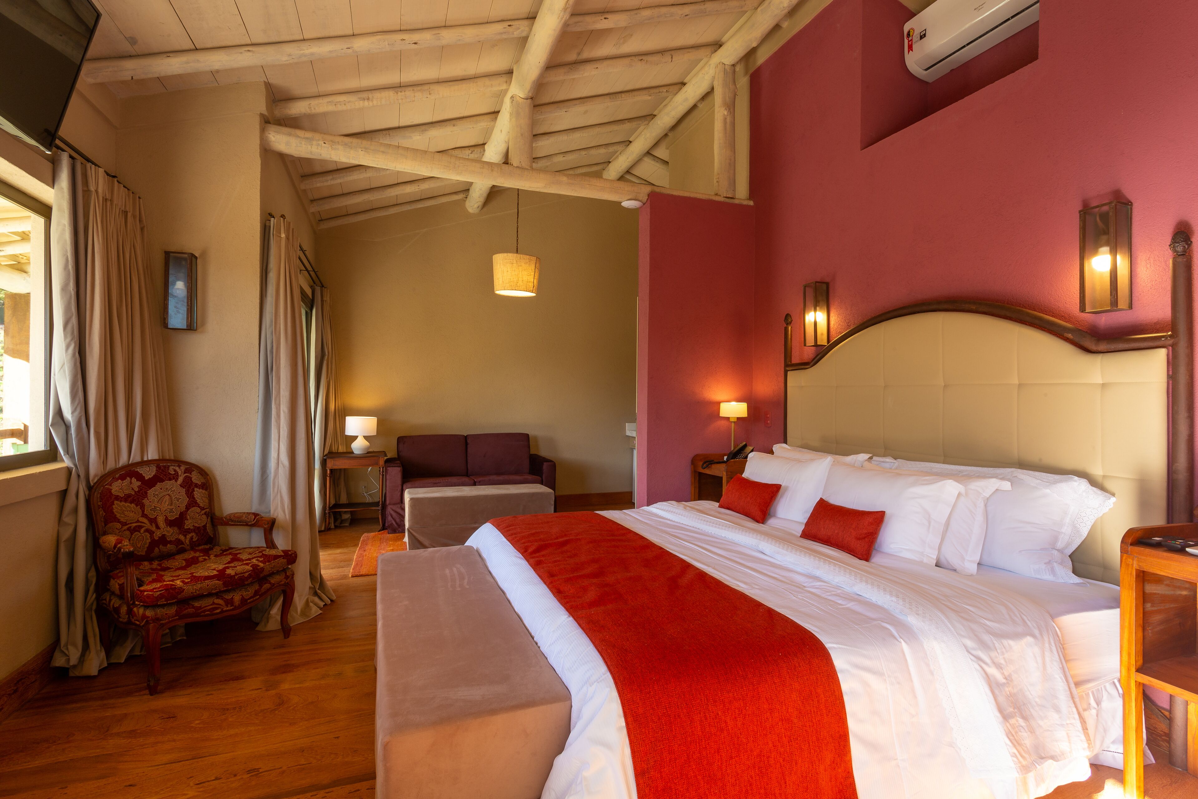 Een hotelkamer met een groot bed, een stoel, een bureau en een raam met gordijnen.