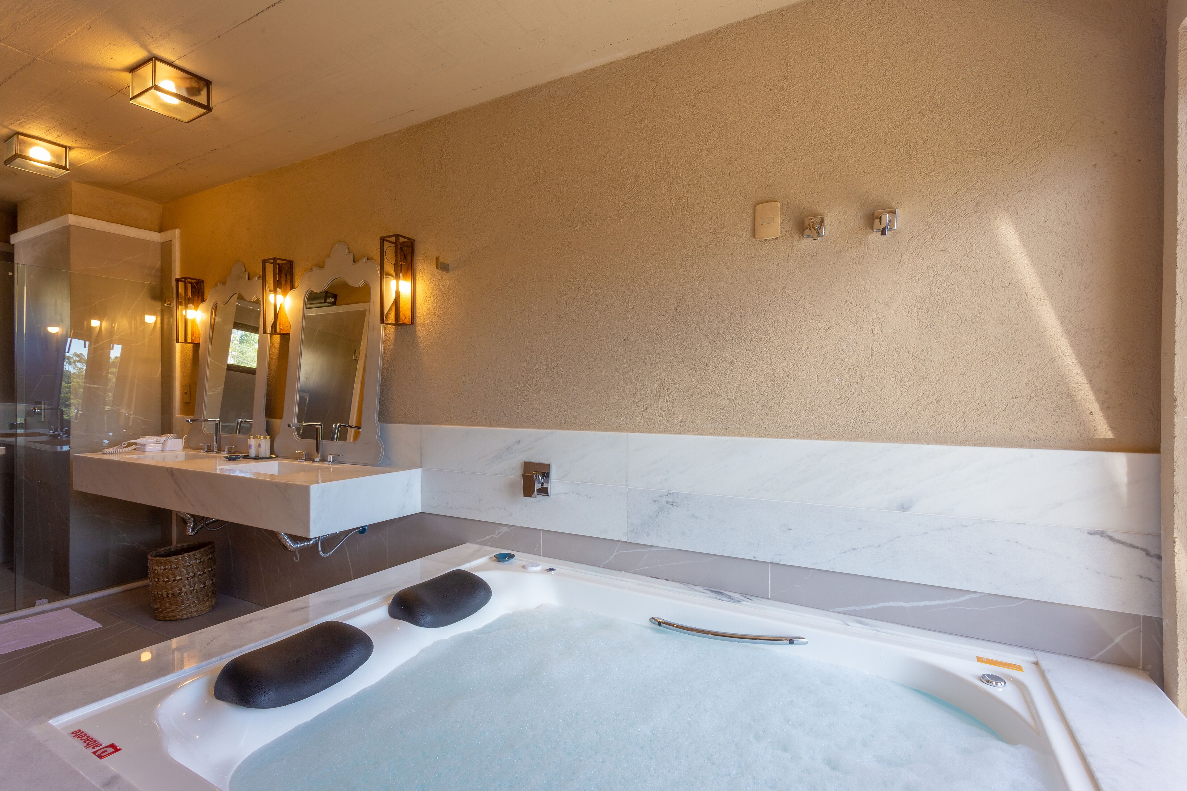 A modern bathroom with a large bathtub, a vanity with mirrors, and wall-mounted lighting.
