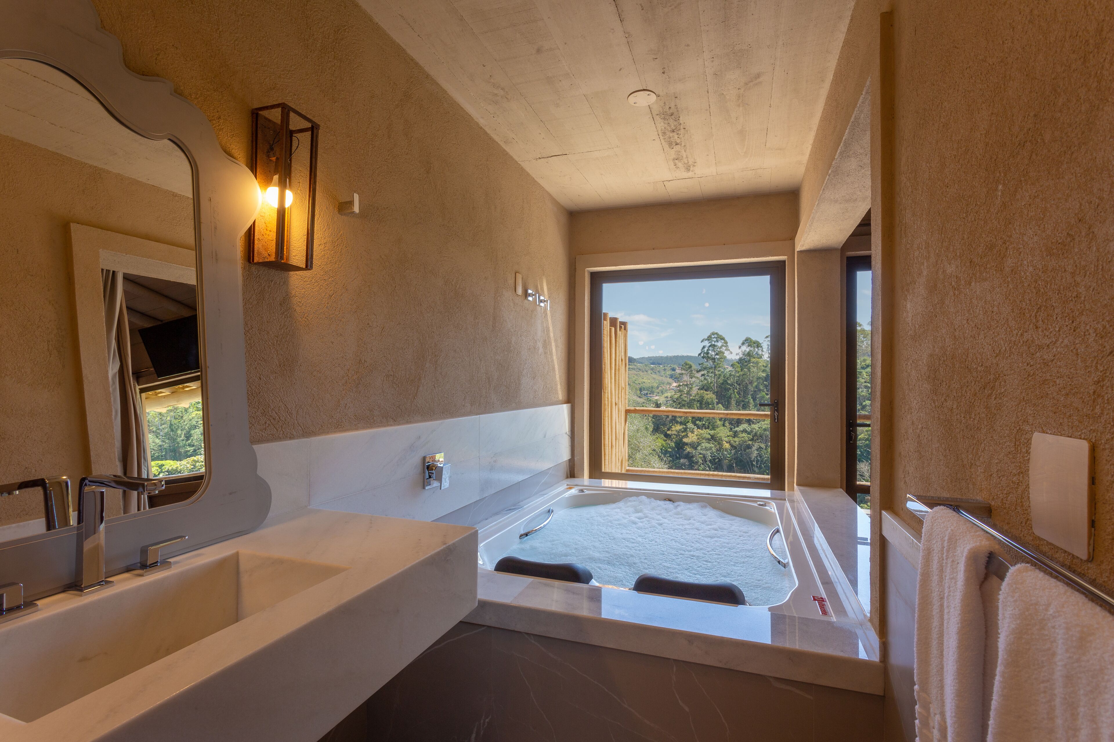A modern bathroom with a large bathtub, a double sink, and a large window offering a view of the outdoors.