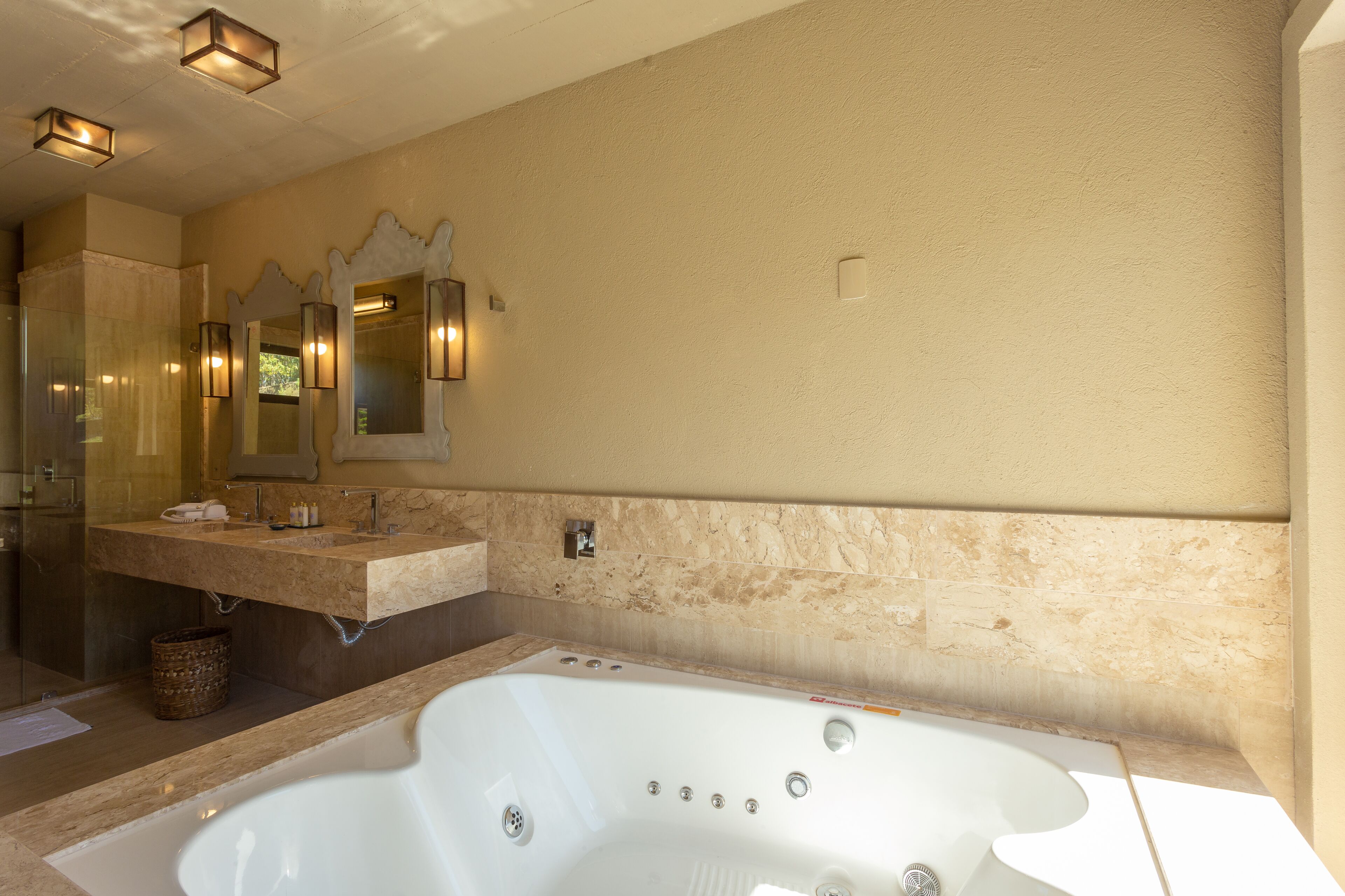 A modern bathroom with a large bathtub, a vanity with a mirror, and wall-mounted sconces.