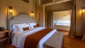 A hotel room with a large bed, wooden headboard, bedside tables, and a bathroom with a bathtub and shower. - Quinta dos Manacás Pousada (Venda Nova Do Imigrante)
