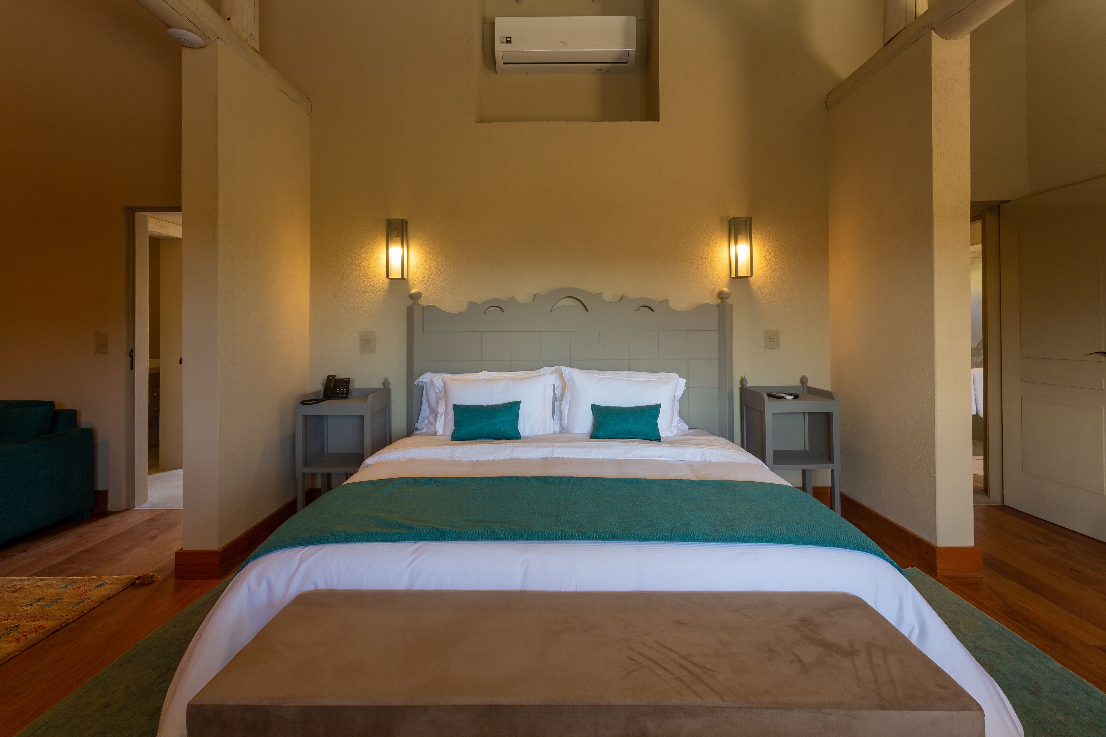 Un dormitorio ordenado con una cama grande, dos mesitas de noche y un escritorio pequeño.