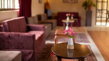 A modern lobby with a sofa, a round table with a vase of flowers, and a guitar in the background.