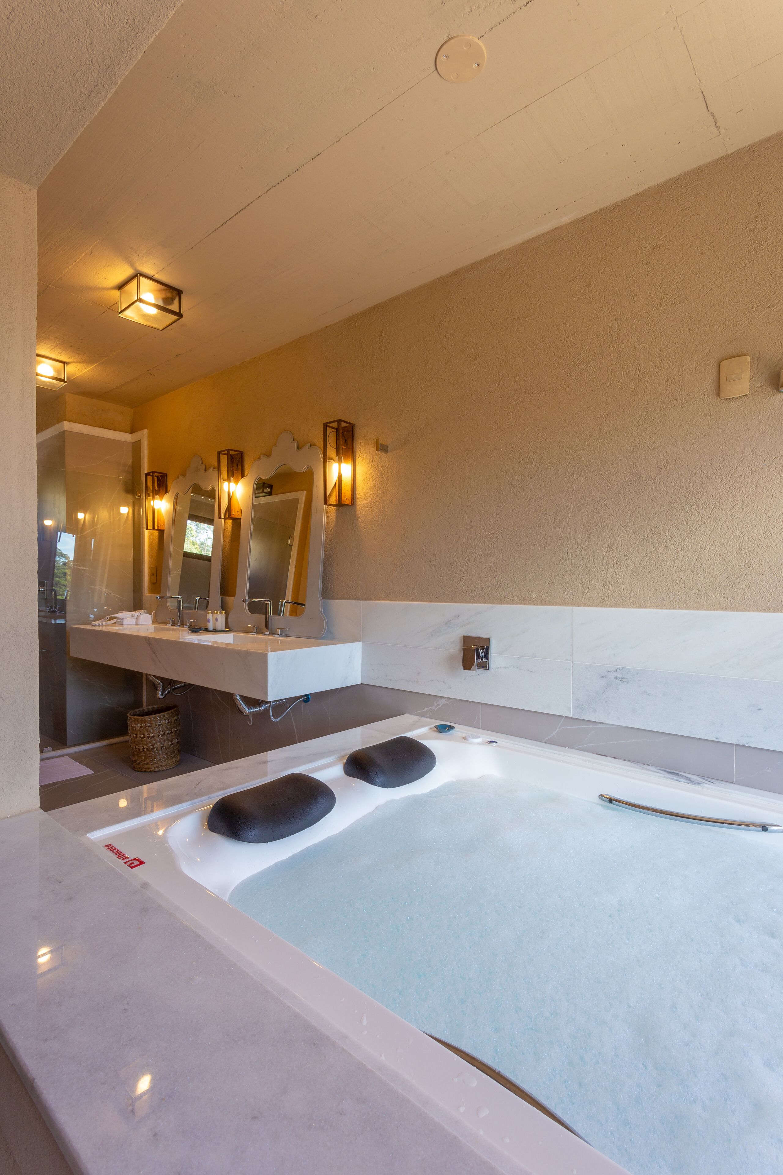 A modern bathroom with a large bathtub, a vanity with three mirrors, and wall-mounted sconces.
