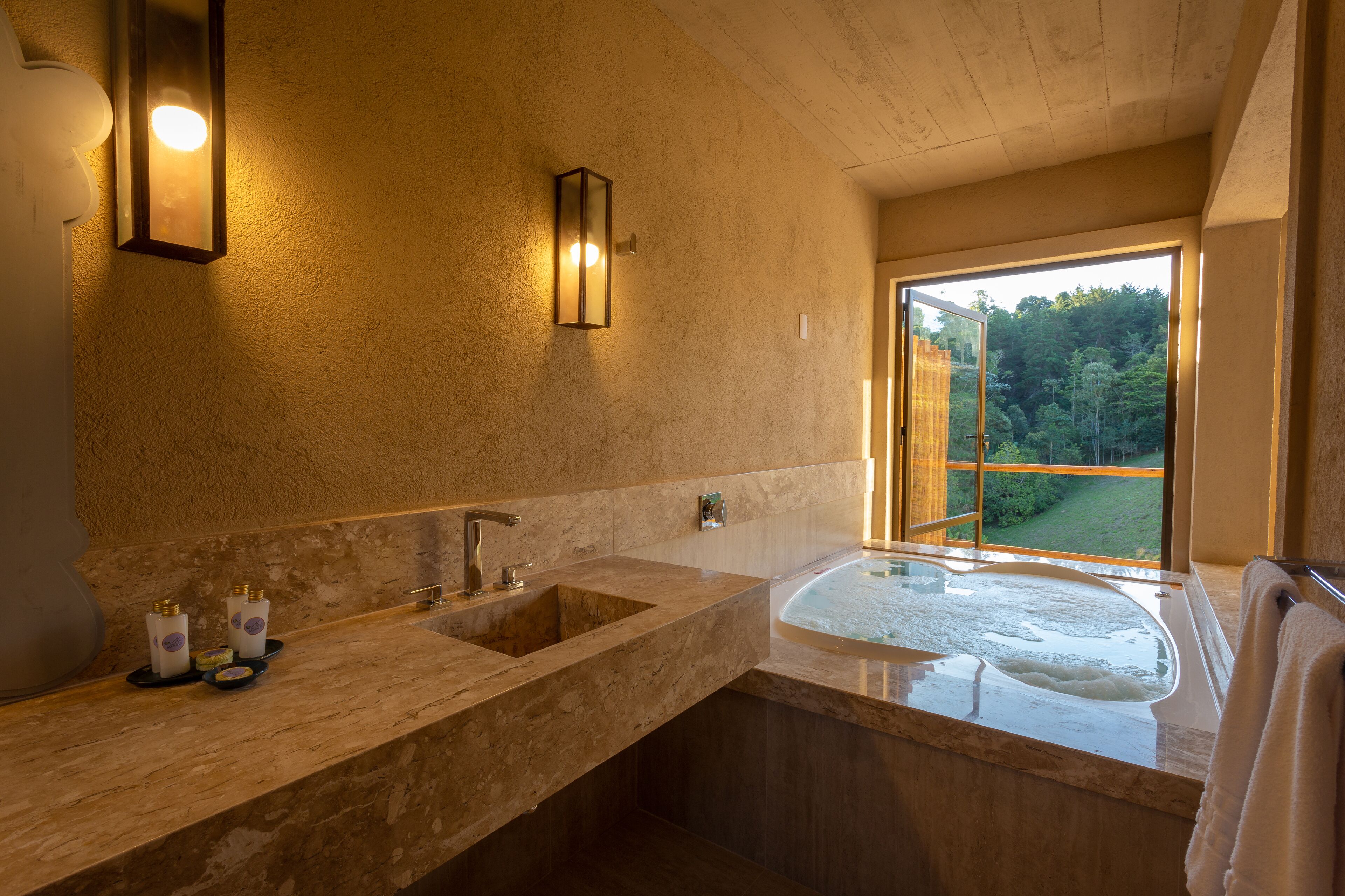 A bathroom with a large sink, a bathtub, and a window with a view of trees.