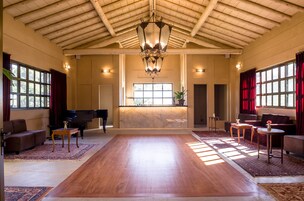 Um quarto espaçoso com piso de madeira, um piano, sofás e uma janela grande.